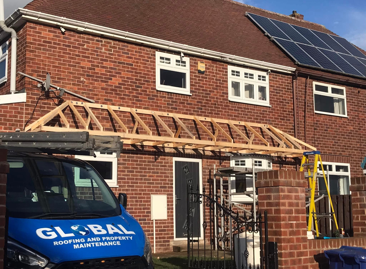 Timber canopy structure being installed outside a brick home